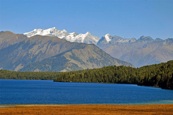 Scenic view of Rara Lake surrounded by pine forests and Himalayan mountains in western Nepal