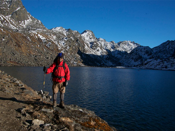 Trekking guide standing with Gosaikunda lake and Lauribina Pass in the background