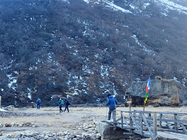 Trekkers walking with proper gear through wooden bridge on Kanchenjunga Circuit Trek Trail